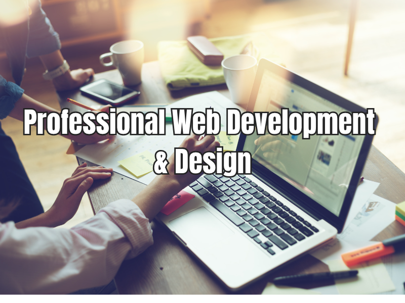 A shot of a desk with two people's hands drawing on a document beside a laptop with the text "Professional Web Development & Design"